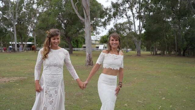 country lesbian brides walking and kissing at farm on wedding day