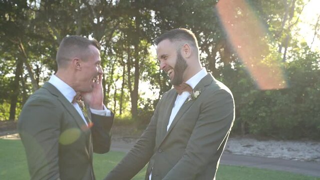 gay groom couple having fun in the forest on wedding day