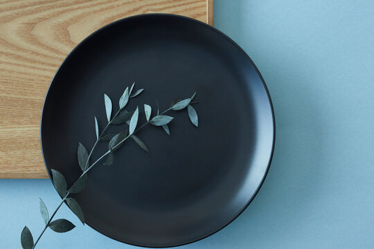 四角の木のトレイと黒い丸の皿に添えたユーカリ