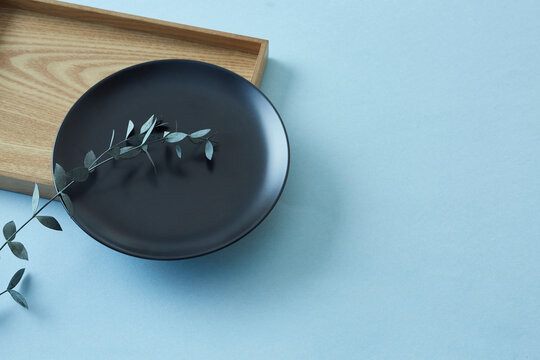 四角の木のトレイと黒い丸の皿に添えたユーカリ