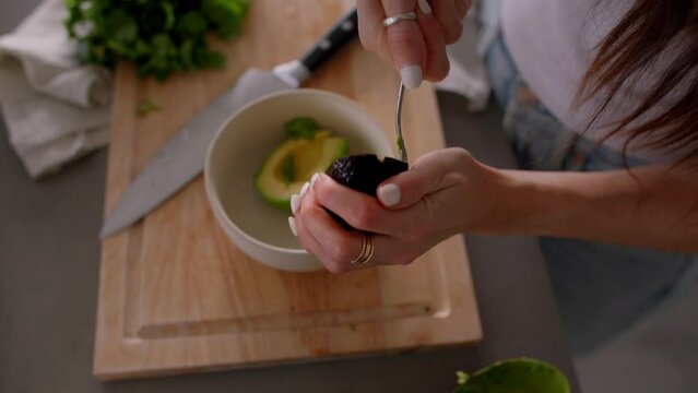 Hands Scooping out fresh avocado into bowl, cooking in kitchen