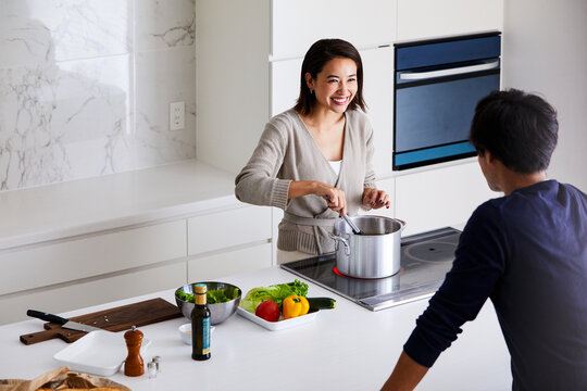 キッチンで料理する女性と眺める男性