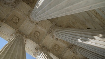 Looking up at the top of Corinthian columns in front of US Supreme Court in Washington, DC, showing...