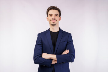 Portrait of young handsome businessman wearing suit standing with crossed arms with isolated on studio white background