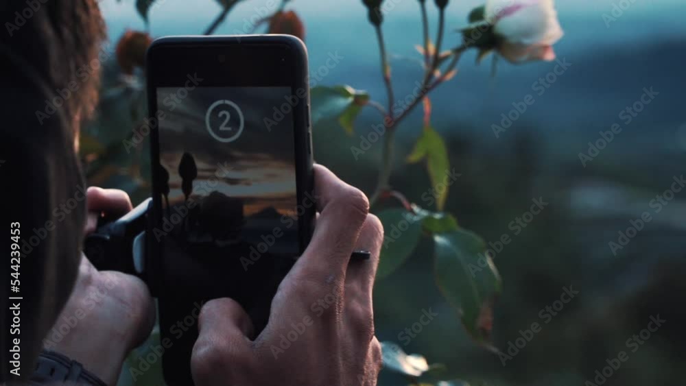 Poster static shot of a man taking landscape photo using smartphone. slow motion.