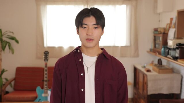 Asian young man smiles at the camera at living room.