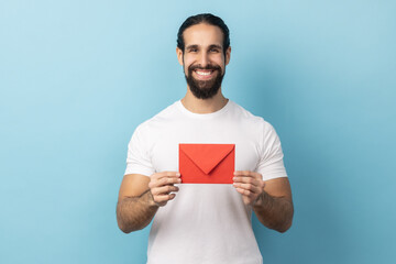 I got love letter on Valentine's day. Portrait of man with beard in white T-shirt holding letter in...