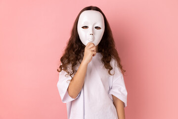 Portrait of unknown anonymous little girl wearing white T-shirt covering his face with white mask,...