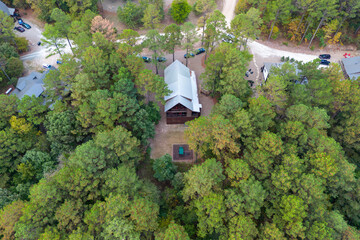 Aerial view of cottages and cars parked nearby in the woods among green trees. Cabins in the forest...