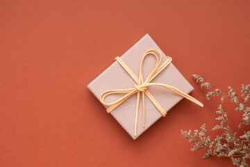 Christmas Winter Season decoration gift box on a copper brown caramel background, natural flowers and leaves