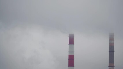 Pipes of an industrial enterprise release white steam with harmful substances into the atmosphere without observing the maximum permitted and permissible standards