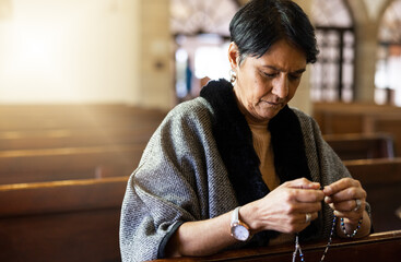 Pray, senior woman and praying in church with a rosary for religion, worship and God praise,...