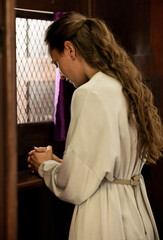 Christian woman, church and confessional, worship and prayer for forgiveness, mercy and peace to holy God, praying and faith. Spiritual person in booth, sorry about sin, secret and trust to priest - obrazy, fototapety, plakaty