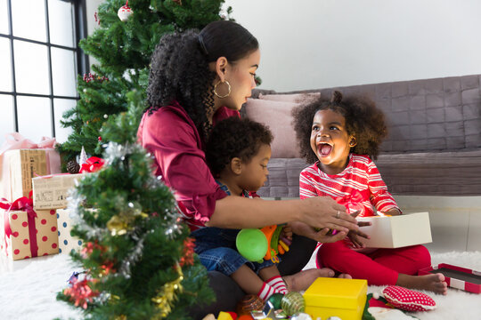 Happy African American family opening Christmas gift box or presents gift at home. Merry Christmas and Happy Holidays