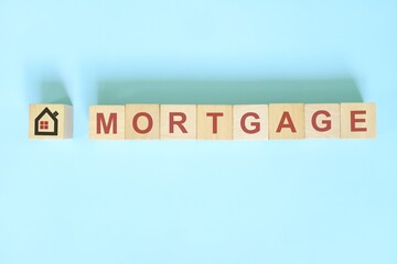 Housing and property mortgage concept in real estate. Wooden blocks typography on blue background.