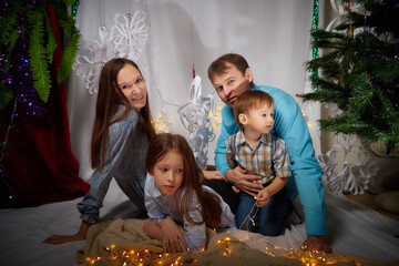 Christmas Family with Kids. Happy Smiling Parents and Children at home. Christmas Tree. Father, mother, sister and brother Celebrating New Year together