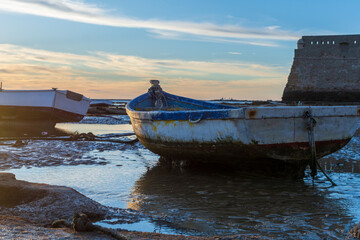 A small wooden fishing boat ashore during a beautiful sunset