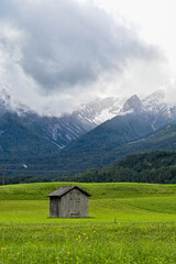 Fototapeta na wymiar Alter Heustadl auf einer Wiese im Tal bei Imst, mit Blick auf die umliegende Berge Muttekopf, Tirol, Österreich