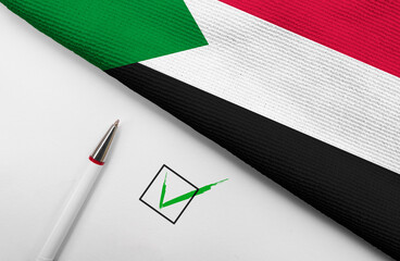 pencil, flag of Sudan and check mark on paper sheet