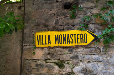 Directional sign showing the way to the famous historic Villa Monastero in Varenna, Province of Lecco, Italy.