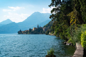 Wide panoramic view of Lake Como and the traditional village of Varenna visible from the walking path along Villa Monastero's gorgeous lakefront garden in Varenna, Province of Lecco, Italy.