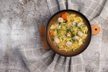 Homemade Meatballs noodle soup in a bowl on a dark background. Top view, flat lay