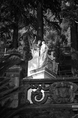 View to ancient sculptures by Giovan Battista Comolli in the botanical garden under the shade of cypress tree of the Villa Monastero in Varenna, on the shore of Lake Como, Province of Lecco, Italy.