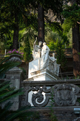 View to ancient sculptures by Giovan Battista Comolli in the botanical garden under the shade of cypress tree of the Villa Monastero in Varenna, on the shore of Lake Como, Province of Lecco, Italy.