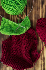 Started knitting on knitting needles, with yarn on a rustic wooden table, with green branches of a Christmas tree.