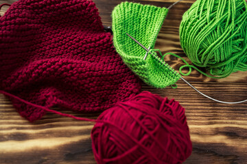 Started knitting on knitting needles, with yarn on a rustic wooden table, with green branches of a Christmas tree.