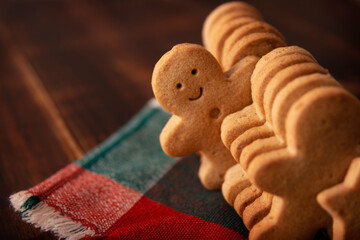 Homemade smiling gingerbread man cookie peeking out from a row of cookies. Standing out from crowd...