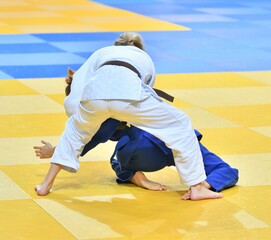 Fighter girls in judogi compete in judo on the tatami