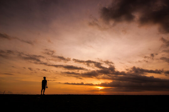 silhouette of man standing on the beach with sunset light