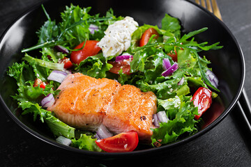 Roasted salmon fish fillet and fresh green lettuce vegetable tomato salad with cream cheese.