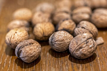 Heap of unpeeled walnuts on wooden table