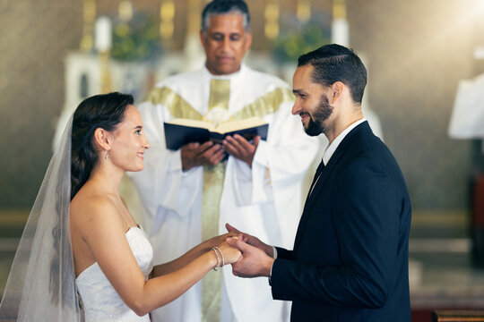 Couple getting married, wedding vows and love commitment at the alter of church during marriage ceremony. Happy bride, groom and Christian priest performing rites, religious and spiritual connection