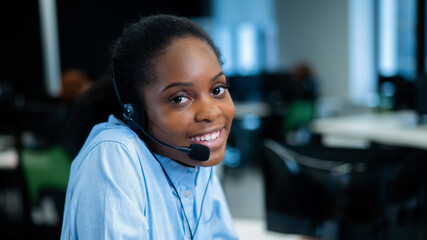 African young woman talking to a client on a headset. Female employee of the call center.