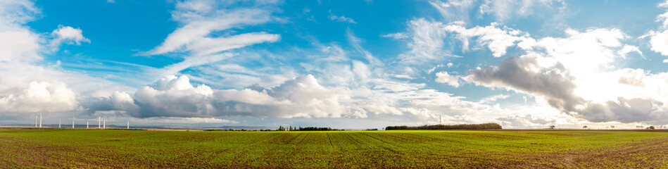 Panorama Web banner of Wind Turbines On Field on moody blue sky background. Landcape scenery with...
