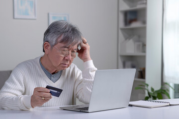 Confused Asian elderly senior retired man, stressed worried sad frustrated male having problem with paying, buying online, payments with credit blocked bank card, laptop. Internet fraud - 544271857