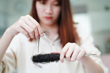 Asian woman have problem with long hair loss attach to comb brush.