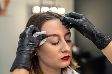 procedure of a beauty salon to paint eyebrows with brush eyebrow dye for client with lashmaker