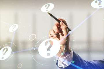Man hand with pen working with abstract virtual question mark illustration on blurred office background. FAQ and search concept. Multiexposure
