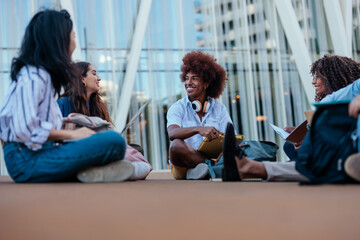 Joyful students sitting on campus ground.