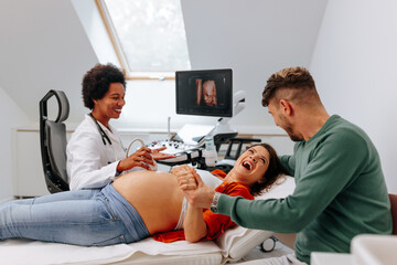 Ecstatic couple having pregnancy ultrasound diagnostic. - obrazy, fototapety, plakaty