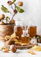 Homemade medlar syrup or juice in three pharmacy glasses with fresh ripe fruits on wooden cutting board. Alternative medicine concept. Copy space. (Mespilus germanica)