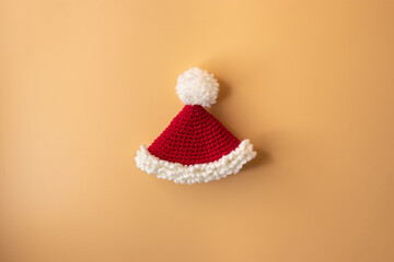 Handmade crochet santa claus hat on orange pastel background. Merry Christmas and happy new year...