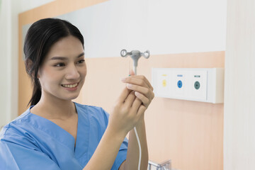 Smiling young Asian nurse adjust saline IV tube for patient in Hospital 
