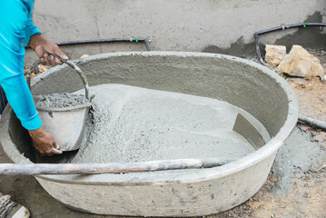 builder contractor man job mix concrete in industry work project, pouring wet liquid material into the big mixing tray in construction site as professional employment