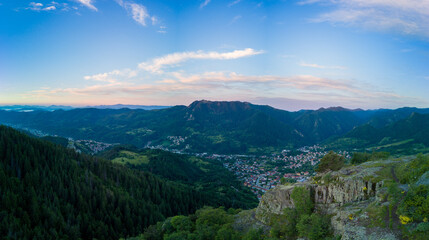 Fototapeta premium Bulgarian town Smolyan with lake, vegetation and clouds. Rhodope Mountains. Panorama, top view