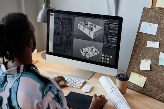 Back view of male digital designer creating 3D architectural model at workplace, copy space